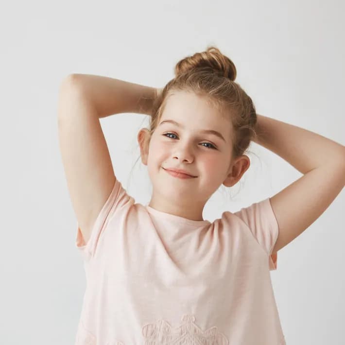 Niña sonriendo con los brazos en alto, segura de sí misma
